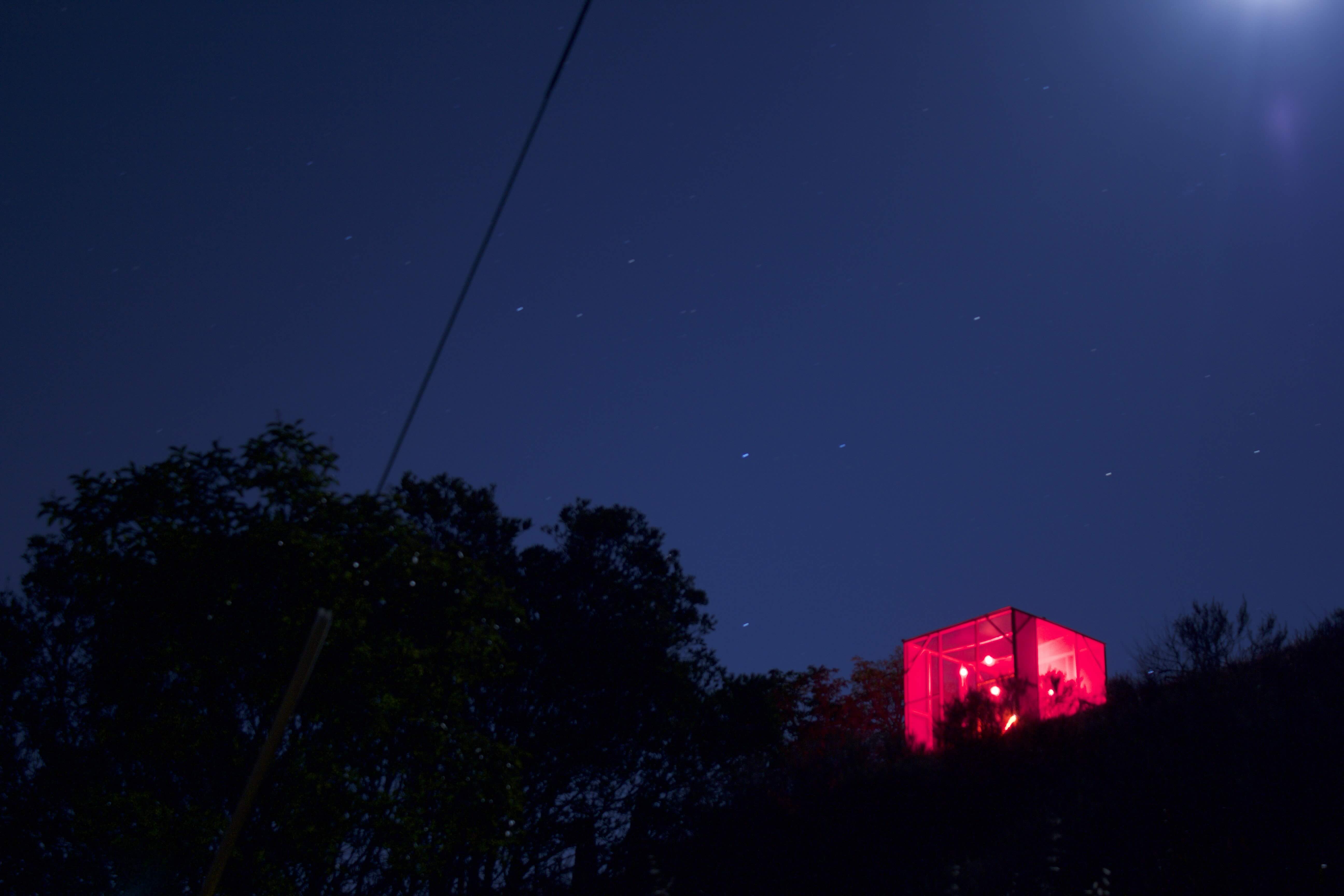 cube seen on top of a mountain at night from bellow